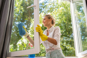 woman cleaning glass window in house